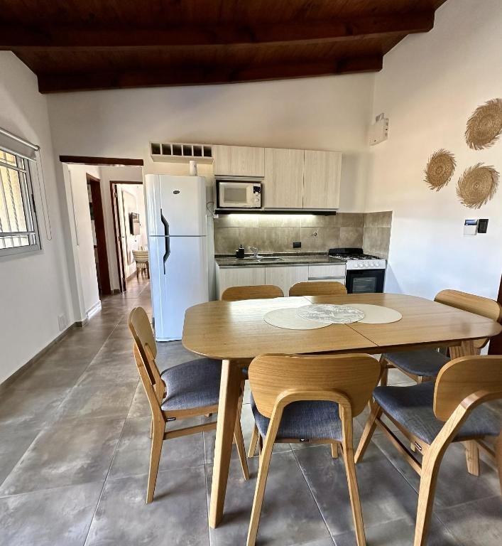 Comedor con mesa de madera para seis y cocina equipada al fondo